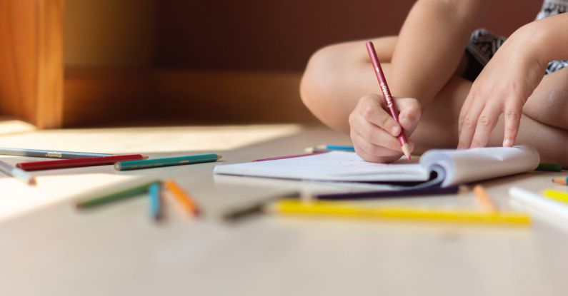 Cognitive Skills - Crop kid sitting on floor and writing in notebook