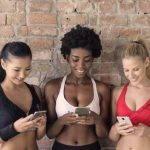 Modular Phones - Three Woman in Assorted-color Sport Bras Holding and Watching Their Smartphones