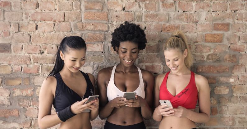 Modular Phones - Three Woman in Assorted-color Sport Bras Holding and Watching Their Smartphones