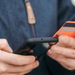 Payment Apps - Anonymous guy with plastic card making online payment using smartphone on street