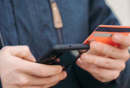 Payment Apps - Anonymous guy with plastic card making online payment using smartphone on street