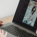 Image Editing - Crop unrecognizable person looking at image on netbook screen while sitting at desk with takeaway coffee