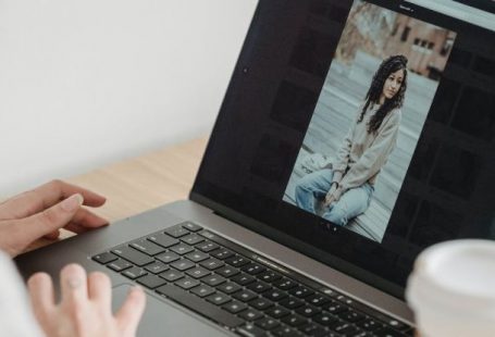Image Editing - Crop unrecognizable person looking at image on netbook screen while sitting at desk with takeaway coffee