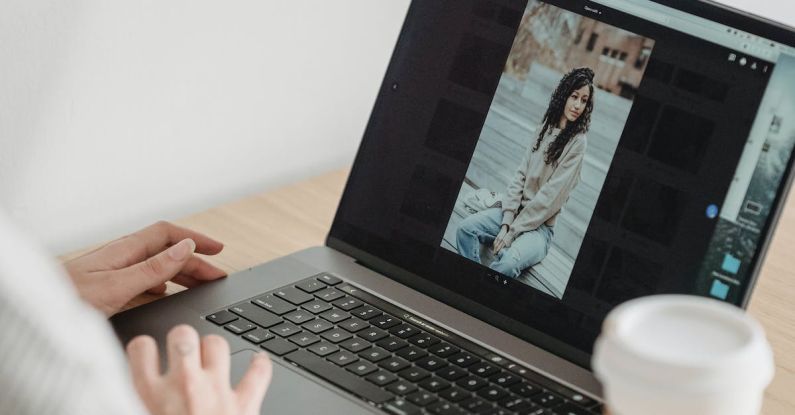 Image Editing - Crop unrecognizable person looking at image on netbook screen while sitting at desk with takeaway coffee